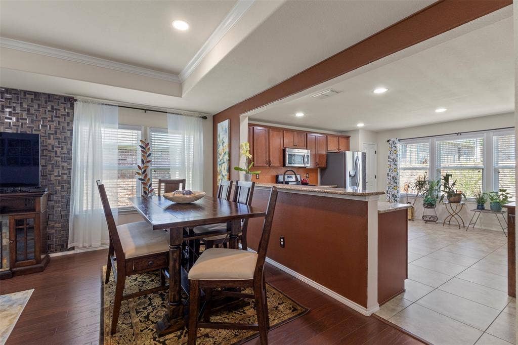 146 Montague Lane, Frisco, TX 75036 Open-concept living space with wood-finish flooring, a tray ceiling, recessed lighting, and kitchen with wood cabinetry and stainless steel appliances
