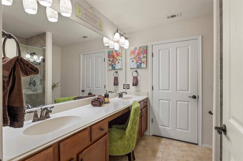 146 Montague Lane, Frisco, TX 75036 Dual vanity with integrated sinks, expansive counter space, wood-finish cabinetry, and tiled flooring
