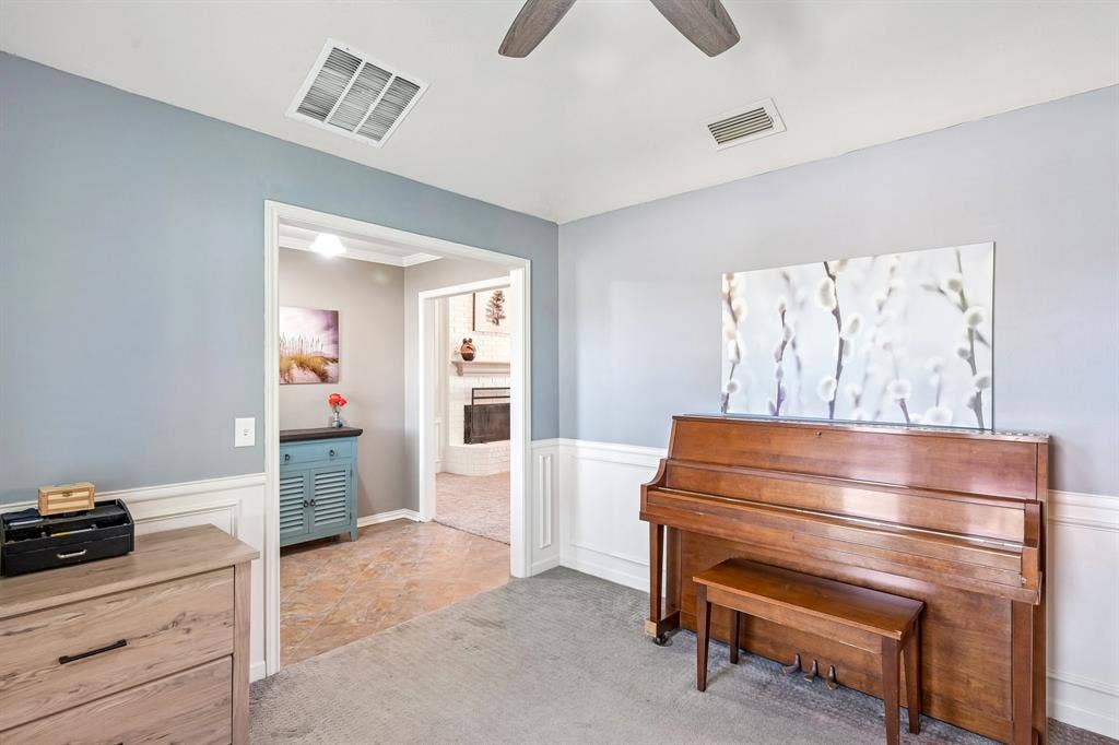 3441 Sheffield Circle, Plano, TX 75075 Carpeted room with wainscoting and light blue wall paint, featuring a ceiling fan