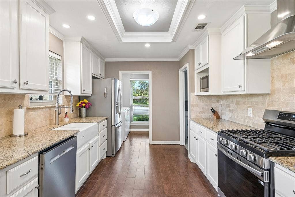 3441 Sheffield Circle, Plano, TX 75075 Kitchen featuring white cabinetry, granite countertops, stainless steel appliances, a farmhouse sink, and wood-finish flooring