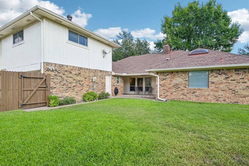 3441 Sheffield Circle, Plano, TX 75075 Expansive green lawn, multi-level brick and siding exterior, privacy fencing, covered patio, and a skylight feature