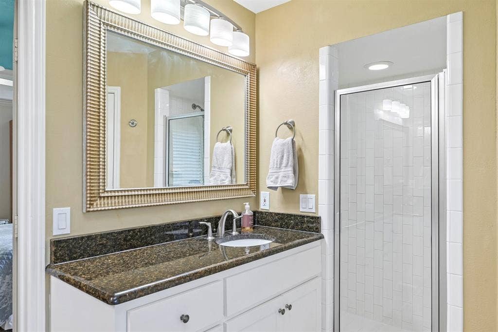3441 Sheffield Circle, Plano, TX 75075 White vanity with dark stone countertop, undermount sink, and chrome faucet