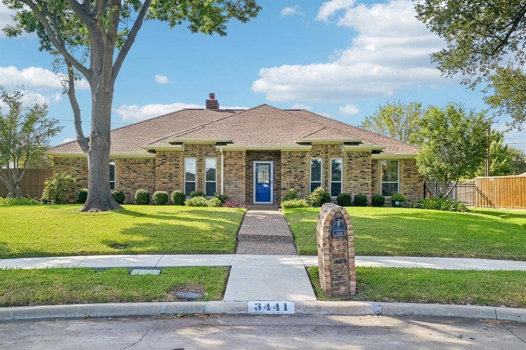 3441 Sheffield Circle, Plano, TX 75075 Brick facade with a contrasting blue front door, mature trees, and a stone-clad mailbox