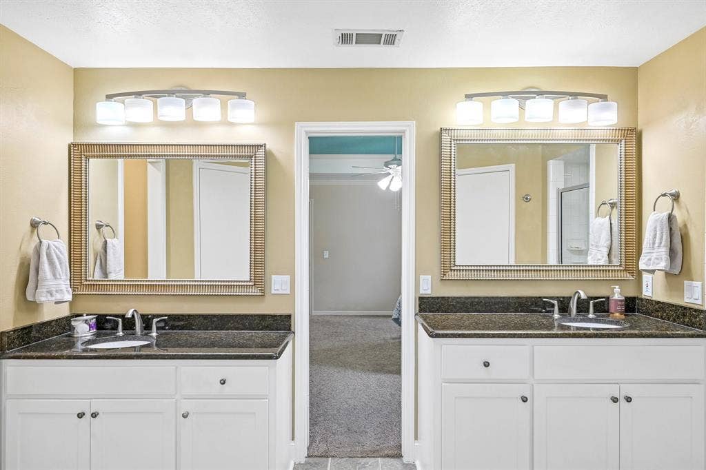 3441 Sheffield Circle, Plano, TX 75075 Dual vanity with white cabinetry, dark countertop, and individual framed mirrors
