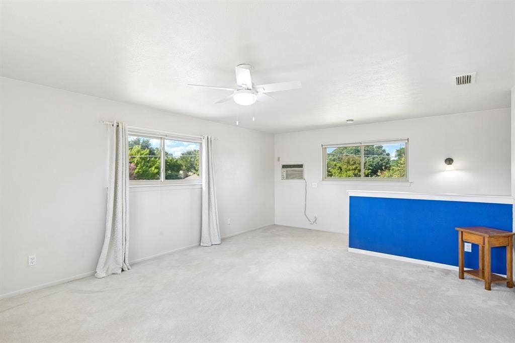 3441 Sheffield Circle, Plano, TX 75075 Expansive room featuring light-toned carpeting, multiple windows, a ceiling fan with integrated lighting, and a wall-mounted sconce