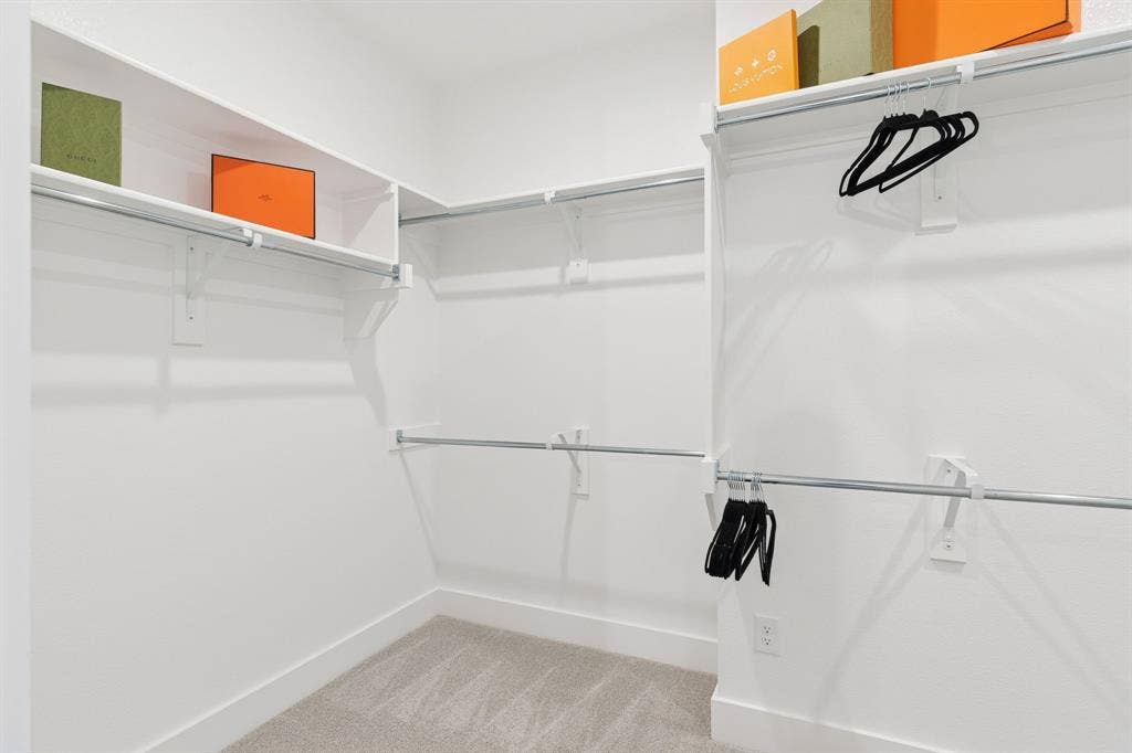1117 Bradford Street, Celina, TX 75009 Walk-in closet featuring light gray carpeting, white baseboards, multiple white shelving units, and chrome hanging rods