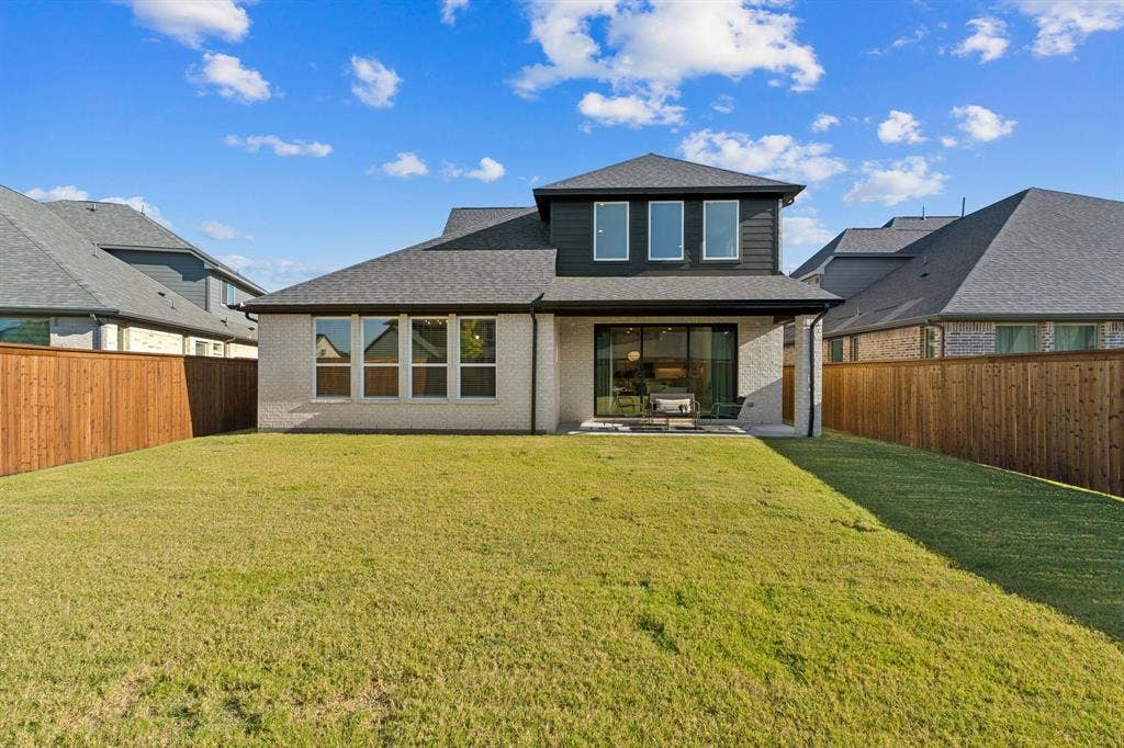 1117 Bradford Street, Celina, TX 75009 Expansive backyard featuring a manicured lawn, a full wooden fence, a covered patio, and large sliding glass doors
