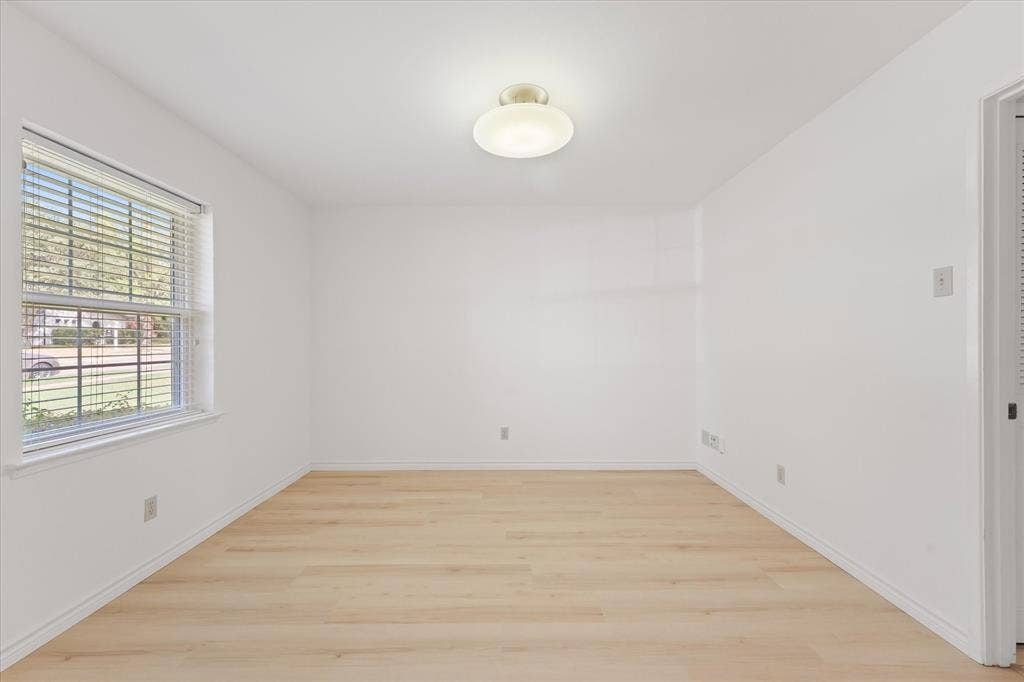 Interior space, perfect for office, featuring wood-finish LVP flooring, a neutral color palette, a multi-pane window with horizontal blinds, and a semi-flush mount ceiling fixture