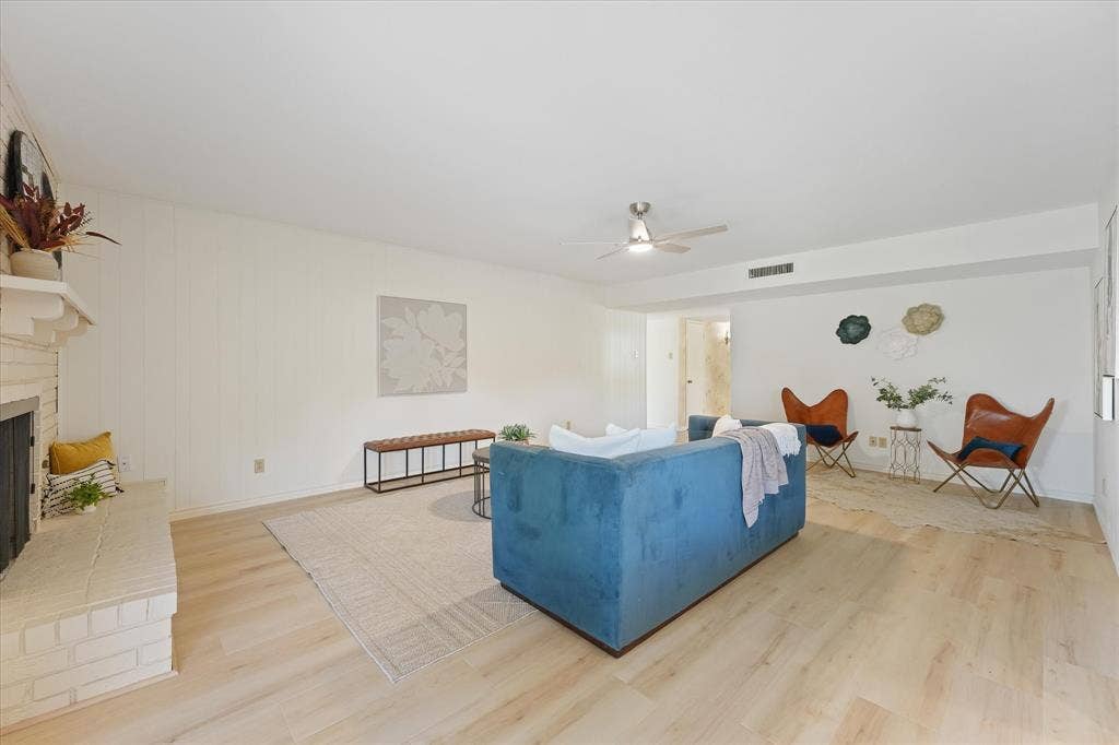 Living area featuring wood-finish LVP flooring, a painted brick hearth fireplace with a mantle, and a ceiling fan
