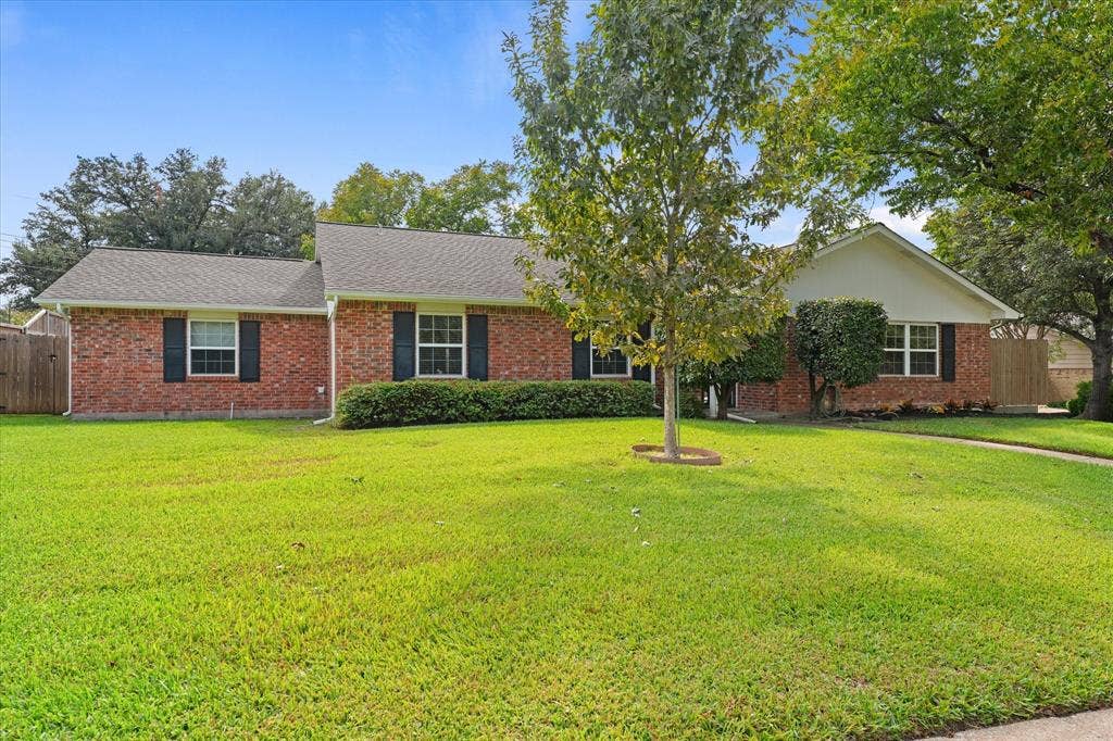 Welcome home to this beautiful single-story brick home in Preston Meadows, with exterior featuring a multi-gable roofline, dark decorative shutters, and expansive lawn landscaping on almost 1/4 acre lot