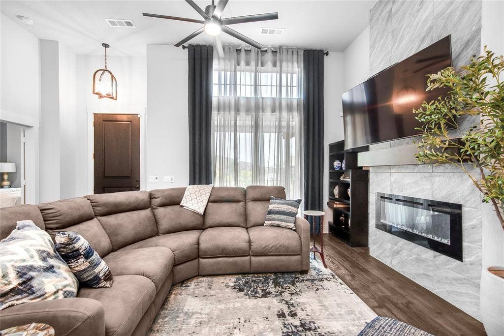 2644 Chardonnay Court, Grand Prairie, TX 75054 Living area with high ceilings, wood-finish flooring, and an electric fireplace set in a stone-tiled wall