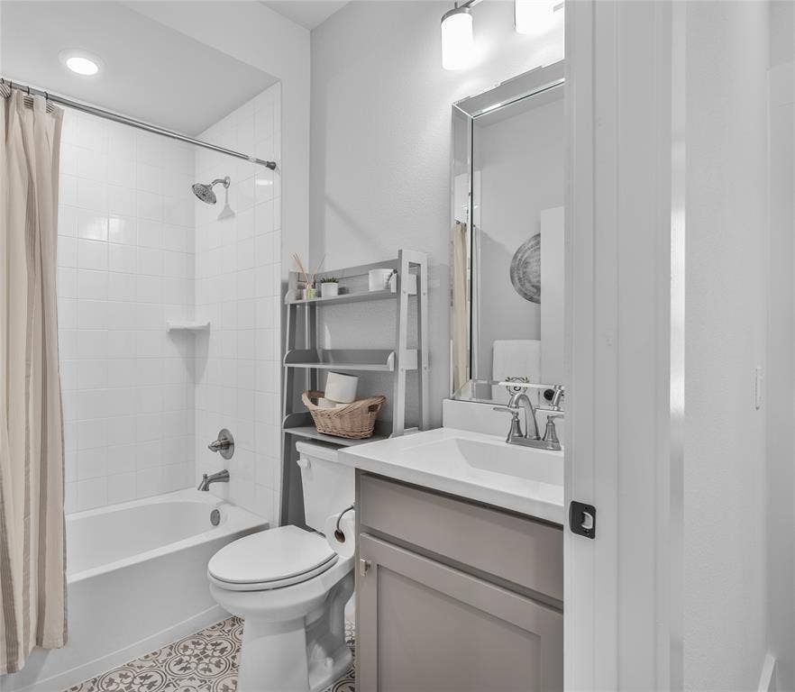 2644 Chardonnay Court, Grand Prairie, TX 75054 Bathroom featuring a white bathtub with tile surround, a built-in vanity with light-toned cabinetry, a rectangular sink, and a decorative mirror
