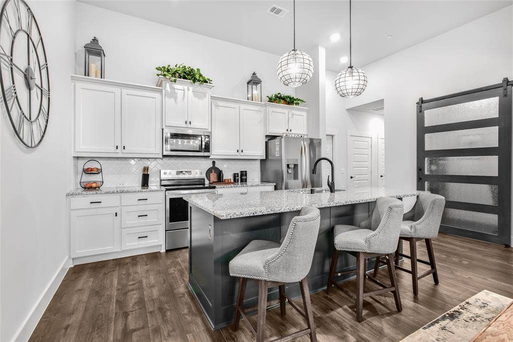 2644 Chardonnay Court, Grand Prairie, TX 75054 Kitchen featuring white upper and lower cabinetry, stainless steel appliances, a tile backsplash, and wood-finish flooring