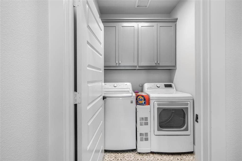 2644 Chardonnay Court, Grand Prairie, TX 75054 Laundry area featuring gray shaker cabinetry, patterned floor tiles, and a white paneled door