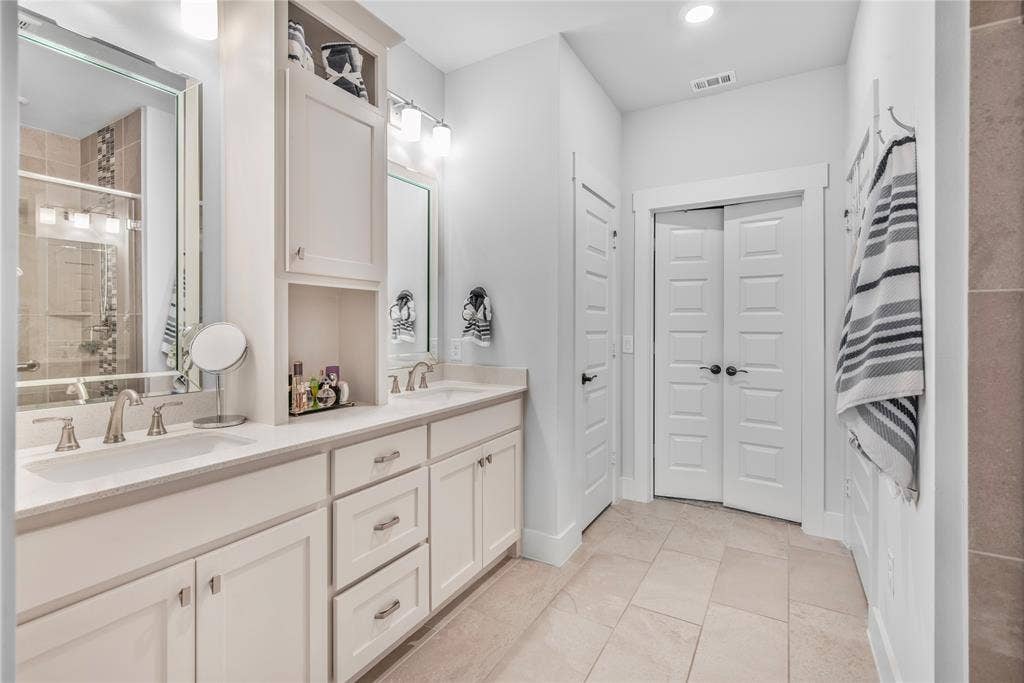 2644 Chardonnay Court, Grand Prairie, TX 75054 Dual vanity with undermount sinks, white cabinetry, integrated storage tower, light tile flooring, and a tiled shower with a glass enclosure