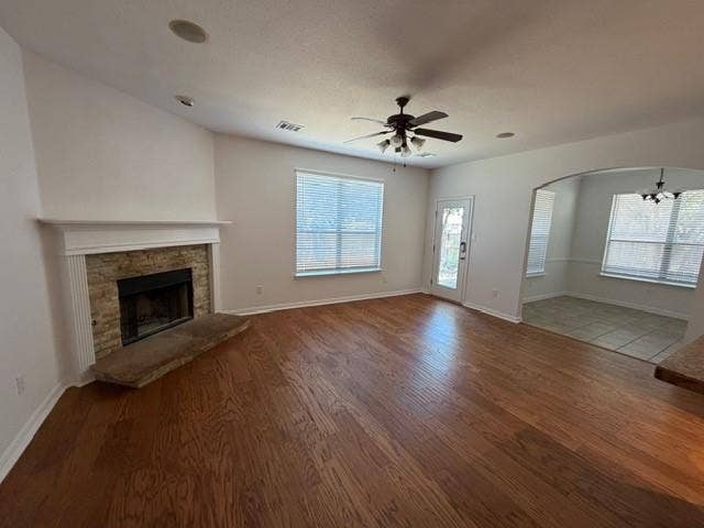 500 Leatherman Drive, Saginaw, TX 76179 Wood-finish flooring throughout, stone-faced fireplace with a substantial hearth, ceiling fan with integrated lighting, recessed lighting, and an arched entryway to the adjoining space