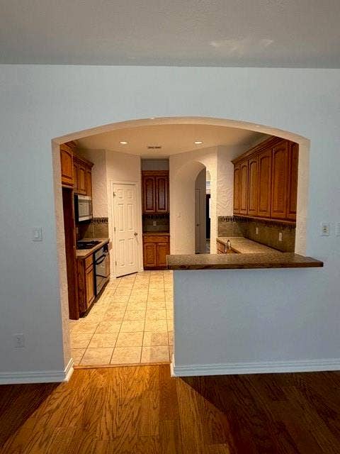 500 Leatherman Drive, Saginaw, TX 76179 Archway opening to kitchen with wood-finish flooring, wood cabinetry, tile flooring, and a breakfast bar