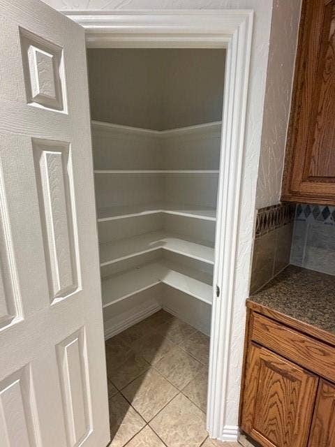 500 Leatherman Drive, Saginaw, TX 76179 Walk-in pantry with extensive corner shelving, tile flooring, and a paneled door