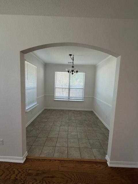 500 Leatherman Drive, Saginaw, TX 76179 Arched entryway opening to a room with tiled flooring, multiple windows with blinds, wainscoting, and a ceiling-mounted light fixture