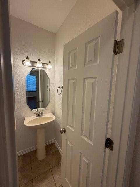 500 Leatherman Drive, Saginaw, TX 76179 Pedestal sink with chrome-finish faucet, octagonal wall mirror, and three-light vanity fixture