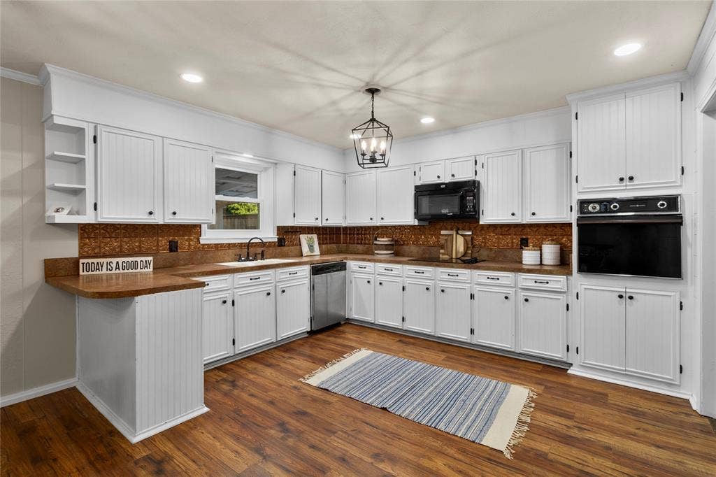Kitchen featuring white cabinetry, wood-finish flooring, built-in oven, integrated microwave, and a black matte faucet