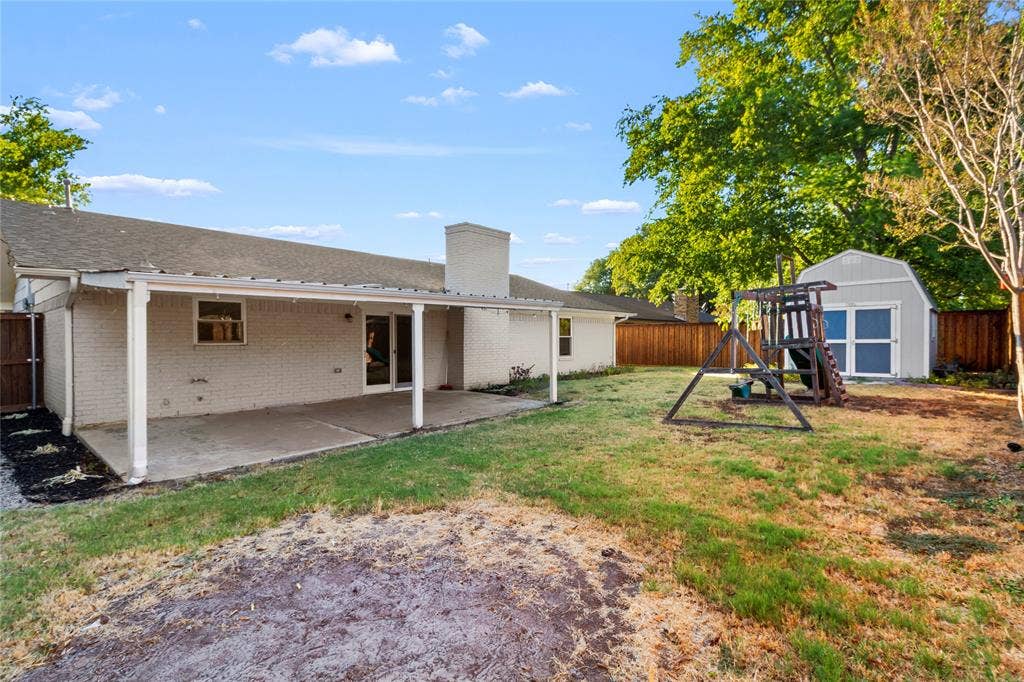 Patio area with concrete surface, white brick exterior, and attached shed