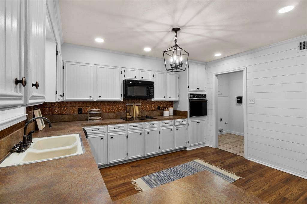 White cabinetry with dark hardware, brown countertops, and a copper-toned backsplash