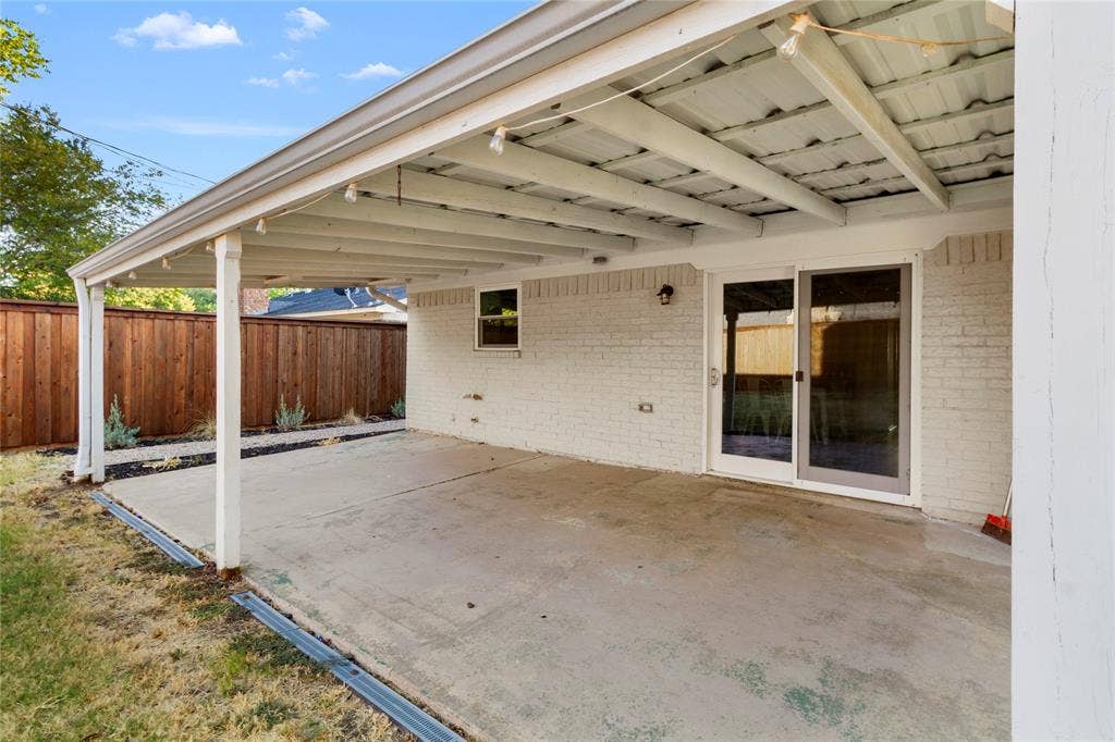 Covered patio featuring a concrete slab and painted brick exterior