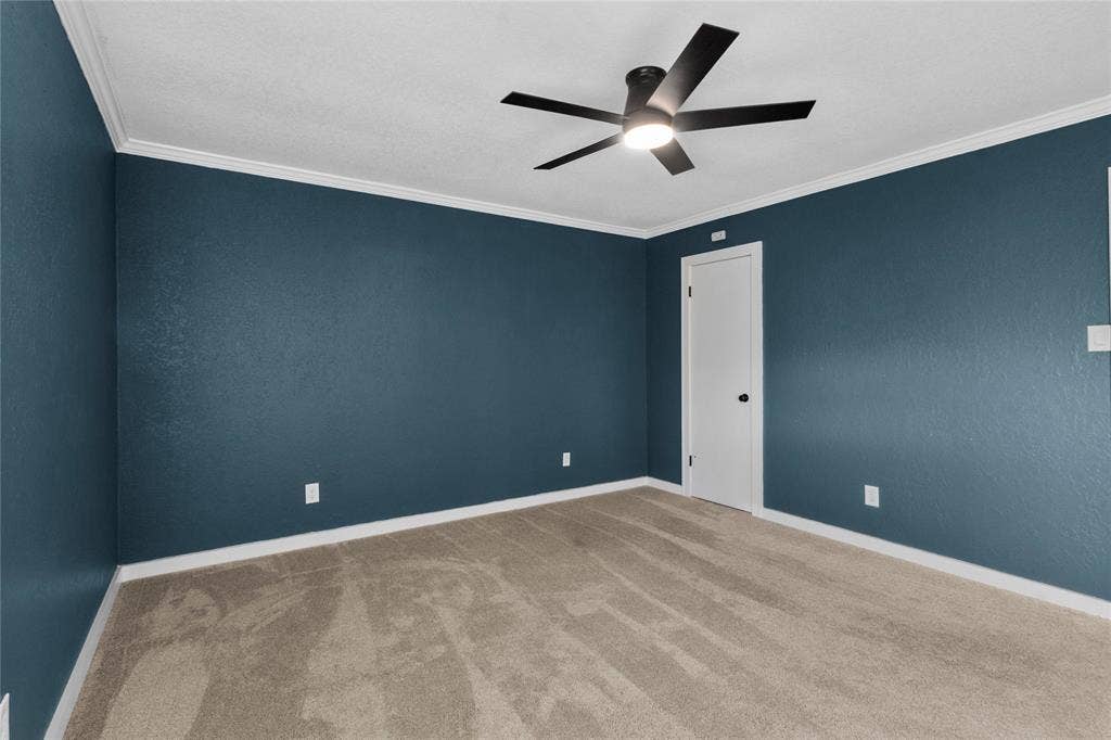 Wall-to-wall carpeting, crown molding, white trim, and a ceiling fan with integrated lighting