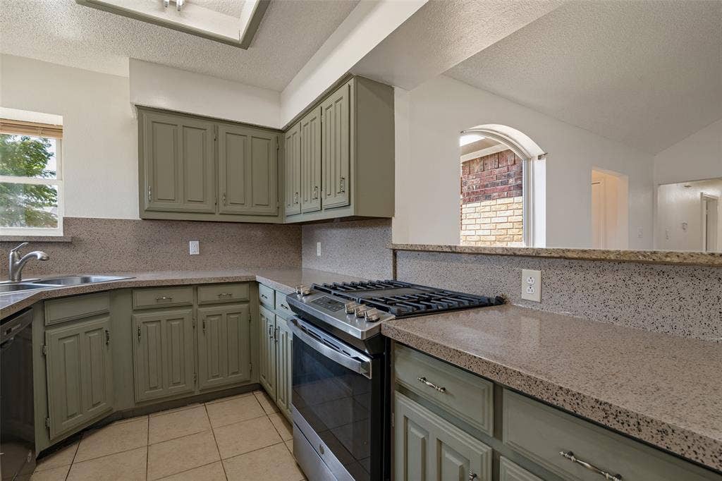 6527 Leasa Court, Sachse, TX 75048 Kitchen featuring light green cabinetry, integrated stainless steel oven with gas cooktop, L-shaped countertop, and tile flooring