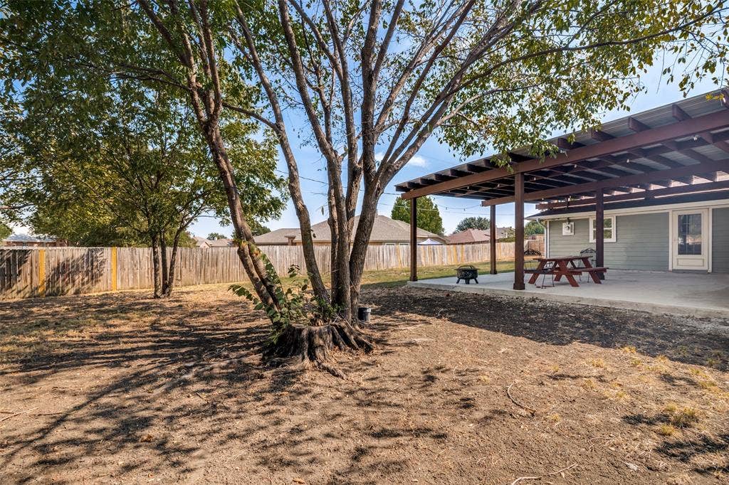 6527 Leasa Court, Sachse, TX 75048 Expansive backyard featuring a concrete covered patio, privacy fencing, and mature trees.