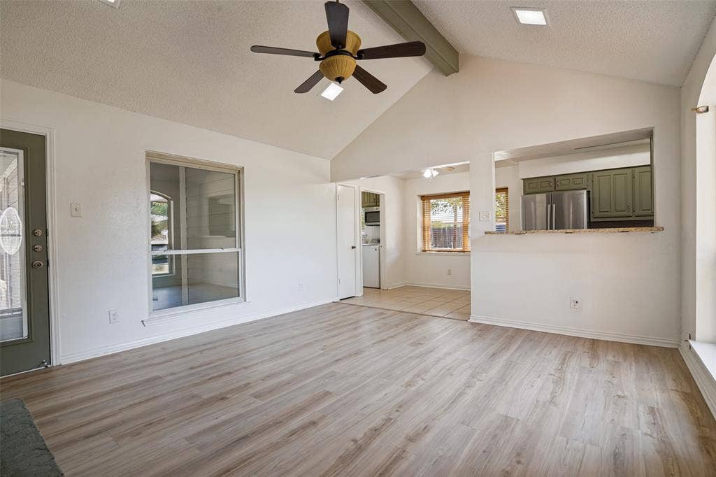 6527 Leasa Court, Sachse, TX 75048 Vaulted ceiling with exposed beam, wood-finish flooring, ceiling fan, breakfast bar pass-through window to the kitchen.