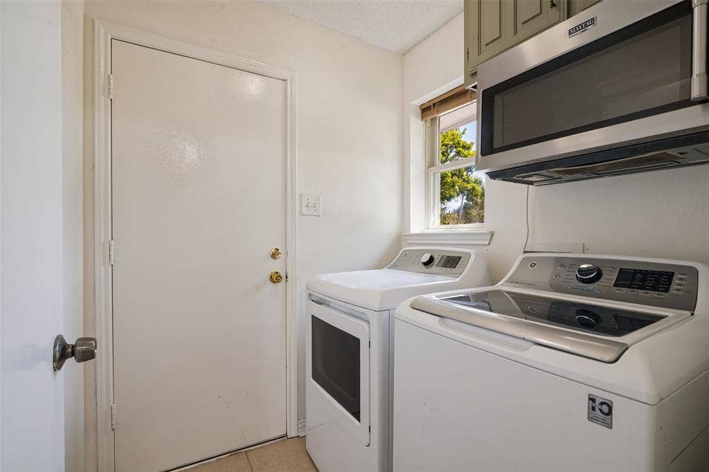 6527 Leasa Court, Sachse, TX 75048 Dedicated laundry room featuring side-by-side washer and dryer with stainless steel finishes, ample cabinetry storage above, and a window providing natural light.