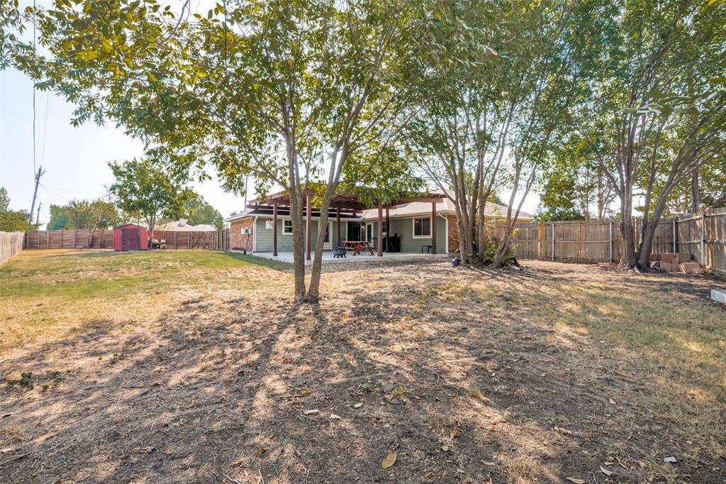 6527 Leasa Court, Sachse, TX 75048 Expansive backyard featuring a covered patio, and mature trees.