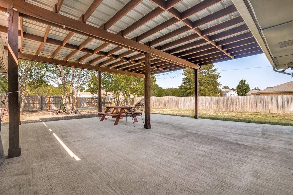 6527 Leasa Court, Sachse, TX 75048 Expansive covered concrete patio with a metal roof and exposed wood beams