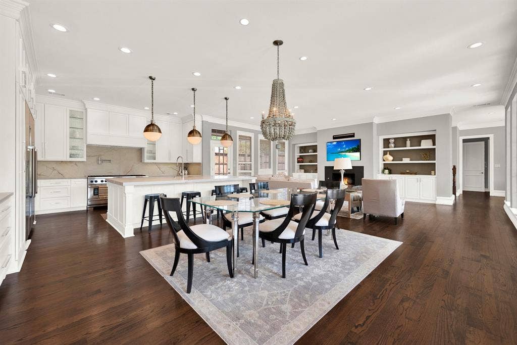 5325 BLAKE Drive, Plano, TX 75093 Rich hardwood floors anchor a massive, light-filled open layout that seamlessly connects the chef's kitchen, casual dining space, and main family room. Warm brass pendants and a beaded chandelier bring modern elegance to this functional hub designed for everyday family gathering