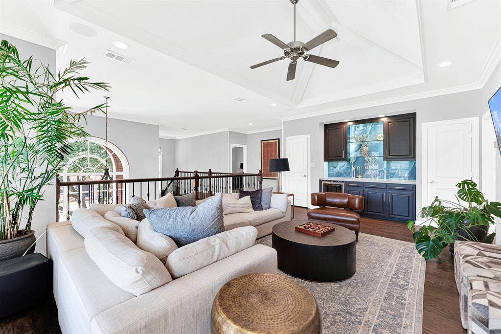 5325 BLAKE Drive, Plano, TX 75093 Designed for host convenience, the upper game room features a wet bar alcove complete with custom blue cabinetry, a beverage fridge, and a statement tile backsplash. Open iron-spindled railings maintain an airy connection to the grand entryway below