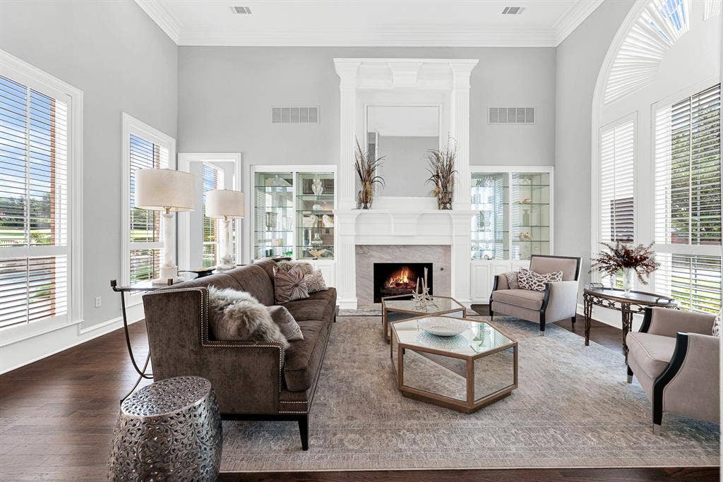 5325 BLAKE Drive, Plano, TX 75093 A refined white fireplace mantel flanked by lighted glass display shelves serves as the centerpiece of this comfortable, bright sitting area. Picture cozy evenings unwinding by the fire while enjoying peaceful views of the landscaped yard through plantation shutters.