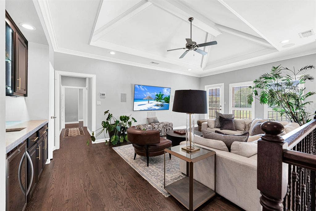 5325 BLAKE Drive, Plano, TX 75093 Anchored by a tray ceiling with an accent fan, this spacious upstairs lounge features a built-in wet bar with dark cabinetry along one wall. Large windows and a glass door open directly to a private balcony overlooking the pool and golf course.