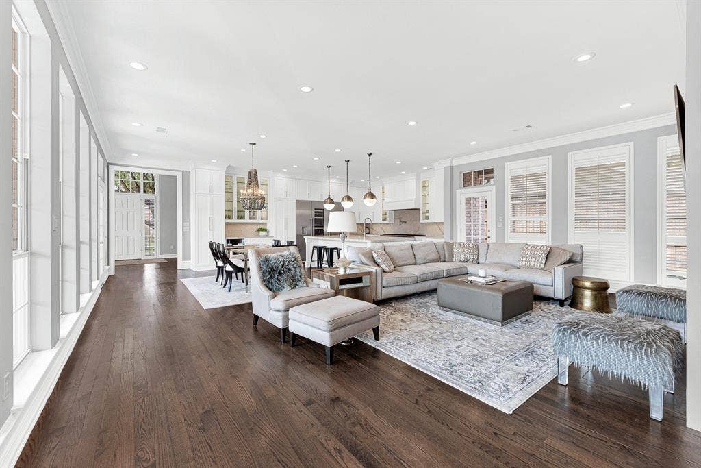 5325 BLAKE Drive, Plano, TX 75093 Rich hardwood floors stretch across this expansive main living area, highlighting the seamless layout connecting the family room, breakfast nook, and kitchen. Recessed lighting and floor-to-ceiling windows brighten every corner, creating an airy atmosphere built for large-scale entertaining.