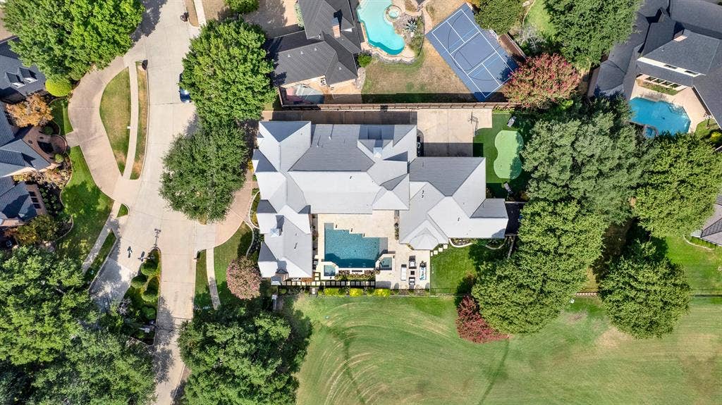 5325 BLAKE Drive, Plano, TX 75093 A precise top-down drone capture perfectly illustrates the property’s scale, from the intricate grey tiled roofline to the functional layout of the pool, putting green, and private circular drive. This unique perspective gives you a true appreciation for the meticulous design and expansive grounds your family will call home.