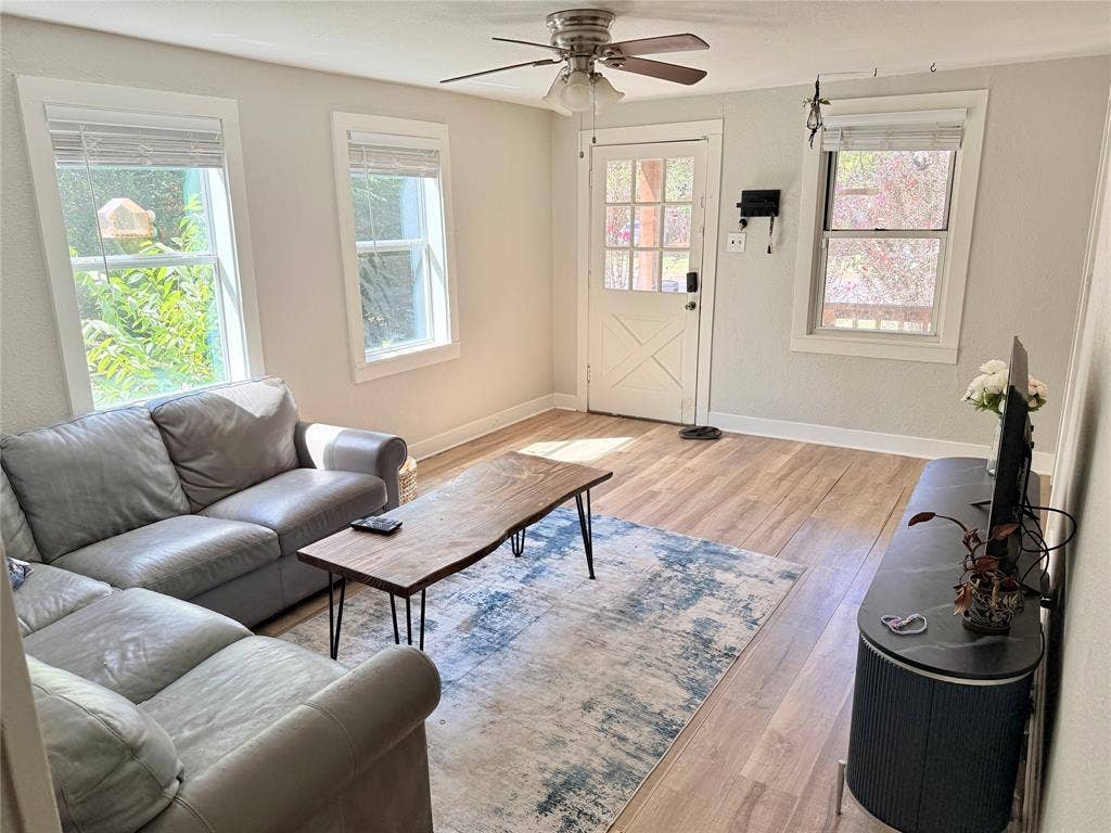 3014 Crestview Street, Tyler, TX 75701 Wood-finish flooring, white trim, multiple windows, ceiling fan with light fixture, and a white door with glass panels