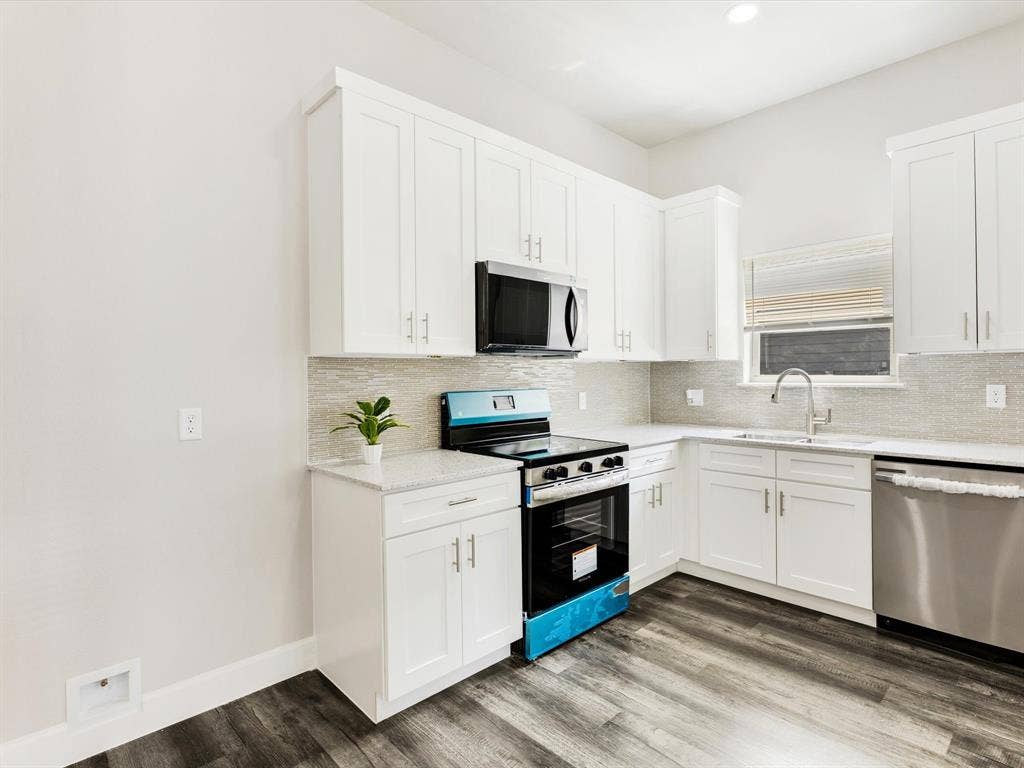 292 Harris Boulevard, Malakoff, TX 75148 Modern kitchen featuring white cabinetry, stone countertops, stainless steel appliances, wood-finish flooring, and a tiled backsplash