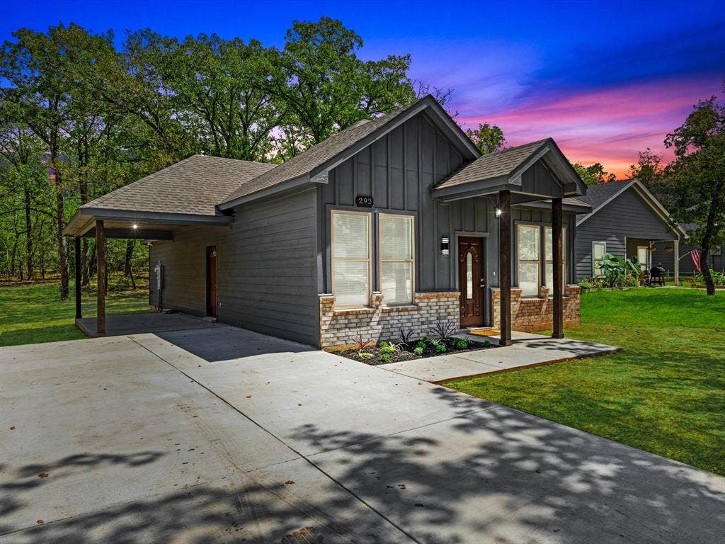 292 Harris Boulevard, Malakoff, TX 75148 Contemporary exterior featuring board and batten siding, stone accents, a covered front entry, a single-car porte-cochère, and a concrete driveway