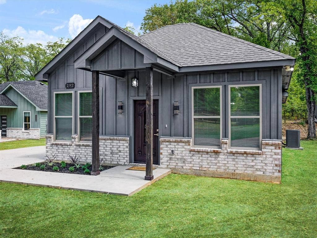 292 Harris Boulevard, Malakoff, TX 75148 Modern exterior featuring vertical siding, a covered porch with substantial columns, a brick facade, and an asphalt shingle roof