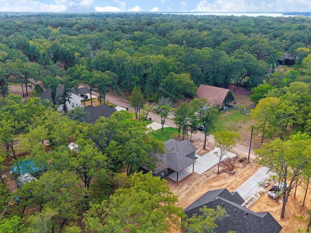 292 Harris Boulevard, Malakoff, TX 75148 Expansive wooded surroundings with a new construction property featuring a dark shingle roof and concrete driveway