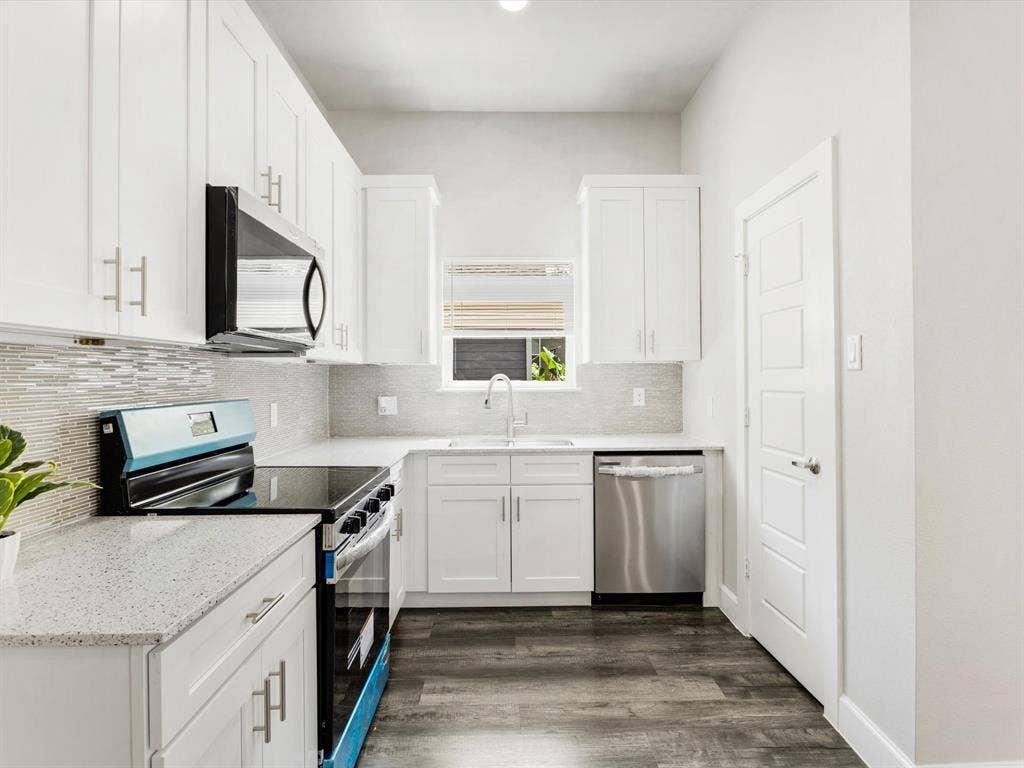 292 Harris Boulevard, Malakoff, TX 75148 White cabinetry with brushed nickel hardware, light-toned countertops, a mosaic tile backsplash, a stainless steel dishwasher, and wood-finish flooring