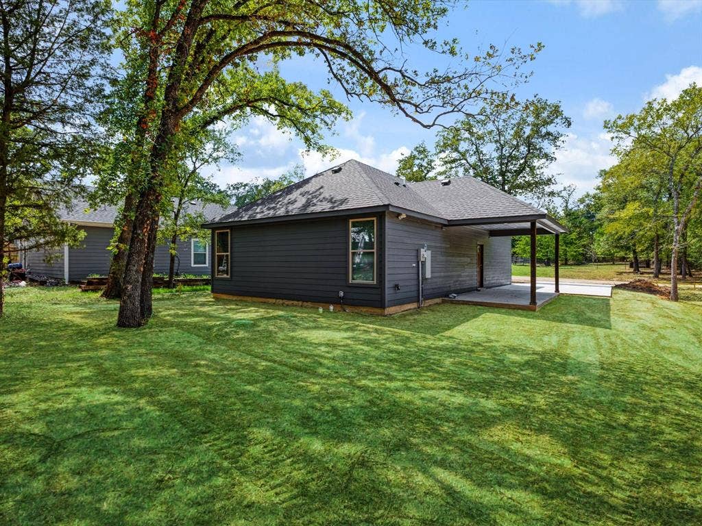 292 Harris Boulevard, Malakoff, TX 75148 Expansive backyard featuring a manicured lawn, mature trees, and a covered patio