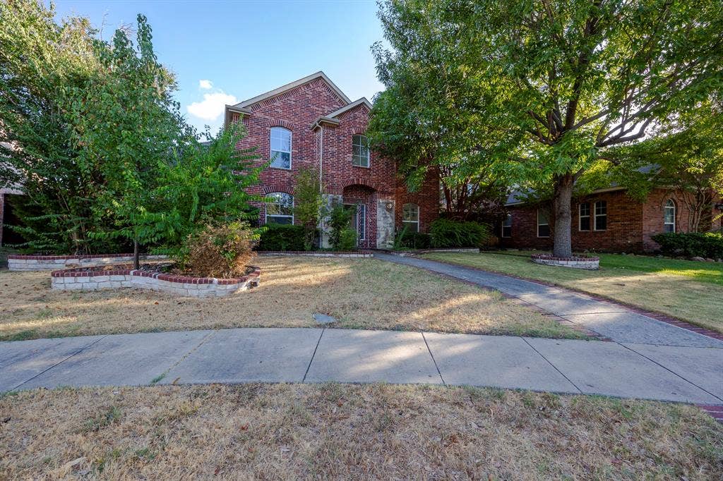 6405 Sapphire Drive, McKinney, TX 75070 Two-story brick exterior with stone accents, arched windows, and mature trees framing the property