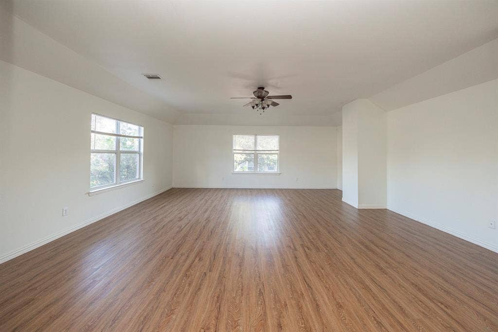 6405 Sapphire Drive, McKinney, TX 75070 Expansive room featuring wood-finish flooring, multiple windows, and a ceiling fan